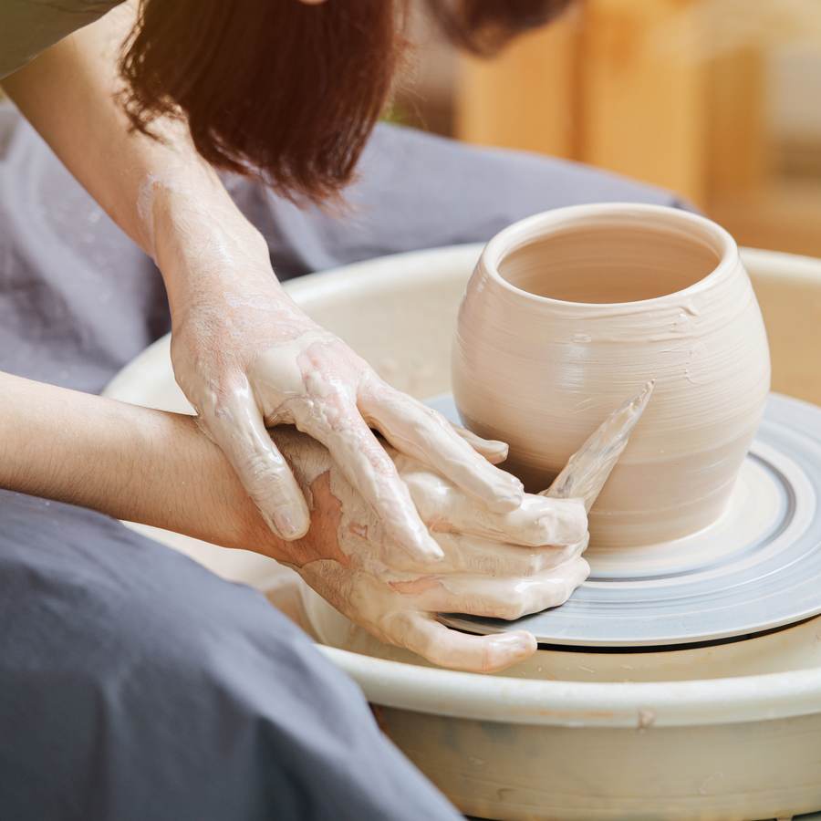 Hands shaping a vessel on the pottery wheel